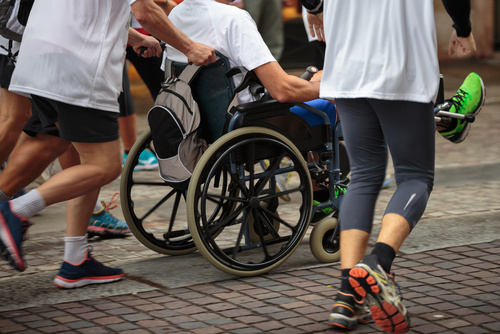 Disabled Athlete in a Sport Wheelchair during Marathon Helped by